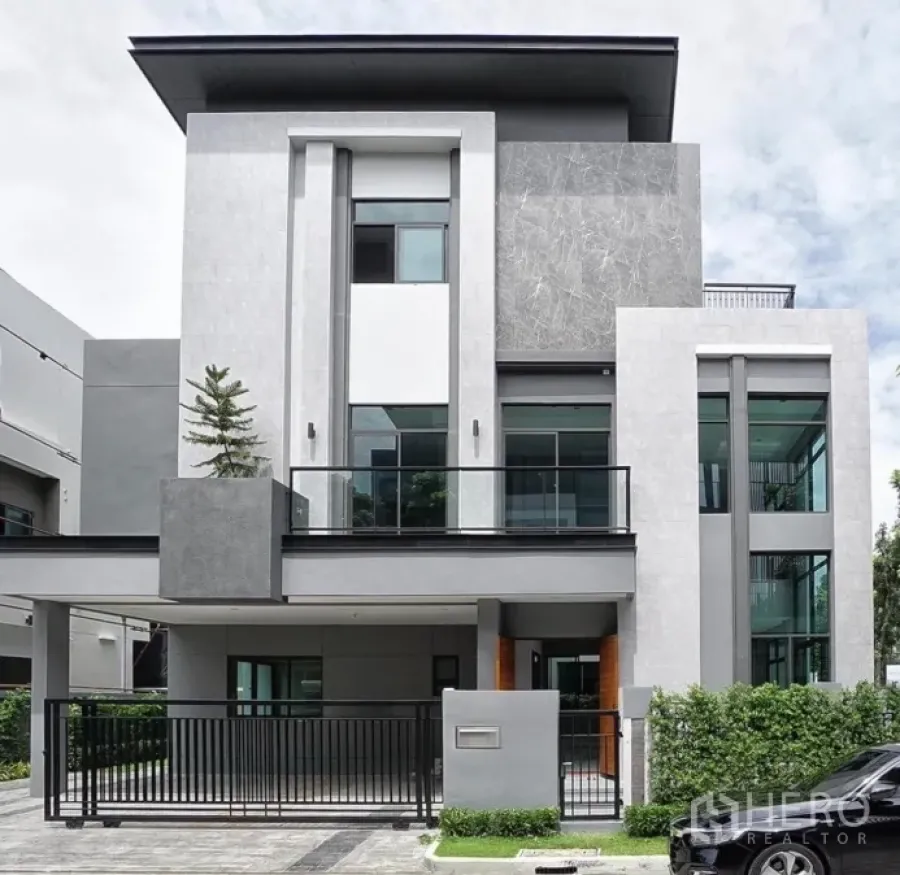 Detached House for rent or sale in Phra Khanong, Bangkok - Contemporary three-storey detached house exterior with balcony, large windows and a gated driveway.