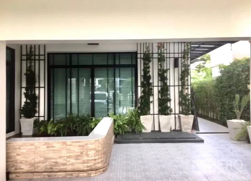 Detached House for sale in Saphan Sung, Bangkok - Covered front porch with planters, trellis detail and tiled flooring beside landscaped hedges.