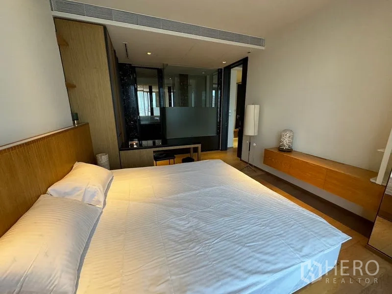 Condominium for rent in Khlong Toei, Bangkok - Bedroom with built-in storage and frosted-glass partition to the marble bathroom.