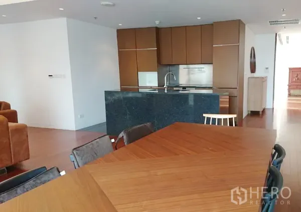 Condominium for sale in Pathum Wan, Bangkok - Modern kitchen with dark stone island, wood cabinetry, built-in appliances and adjacent dining table.