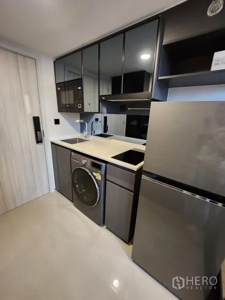 Condominium for rent - Compact kitchen with black cabinetry, quartz countertop, microwave, and refrigerator.