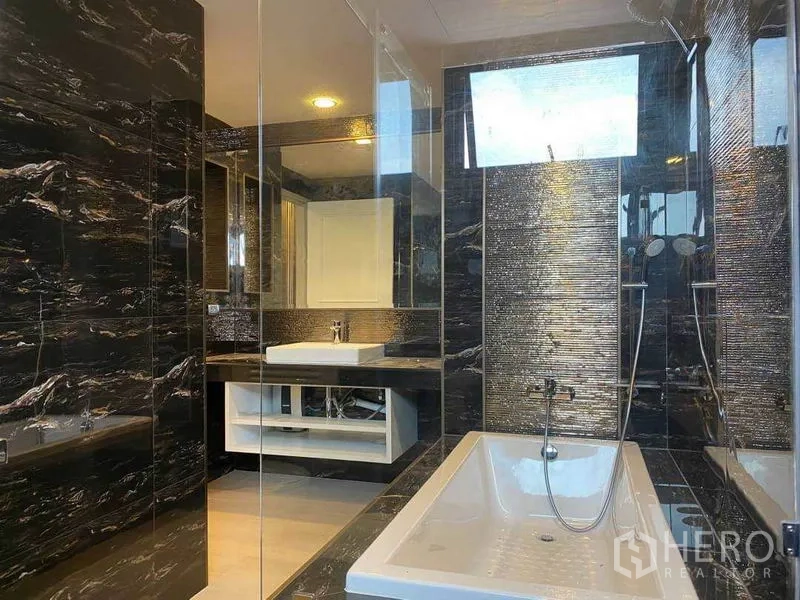 Condominium for rent in Khlong Toei, Bangkok - Luxurious bathroom with bathtub, twin rain showers and vanity behind glass partitions.