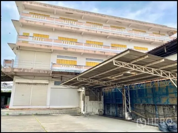 工厂 出租在Chom Thong, Bangkok - 多层工厂楼，黄色百叶窗，带有遮蔽装卸棚。