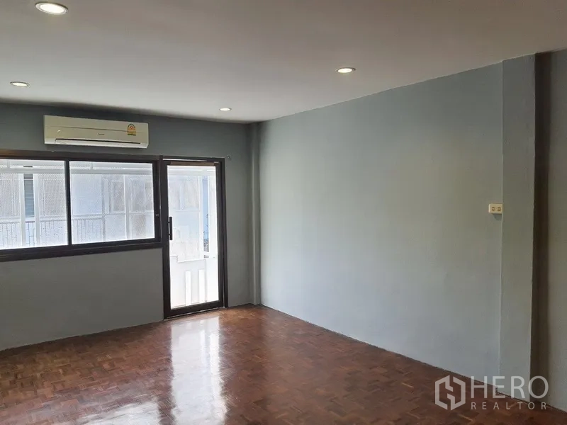 Shophouse for rent in Phra Khanong, Bangkok - Bright room with sliding window, balcony access, and wall-mounted air conditioner.