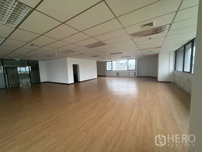 Office Space for rent in Bang Rak, Bangkok - Corner angle showing bright office space with a long window line and white walls.