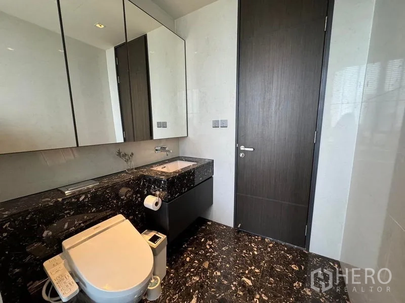 Condominium for rent - Guest bathroom with marble countertop, mirrored cabinets, and bidet toilet.