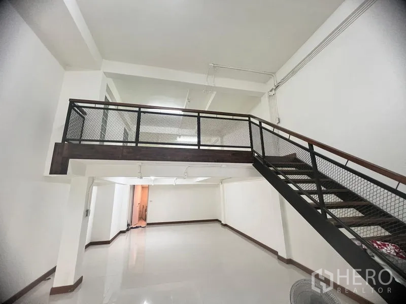Shophouse for rent in Khlong Toei, Bangkok - Double-height retail space showcasing a mezzanine platform and stairs.