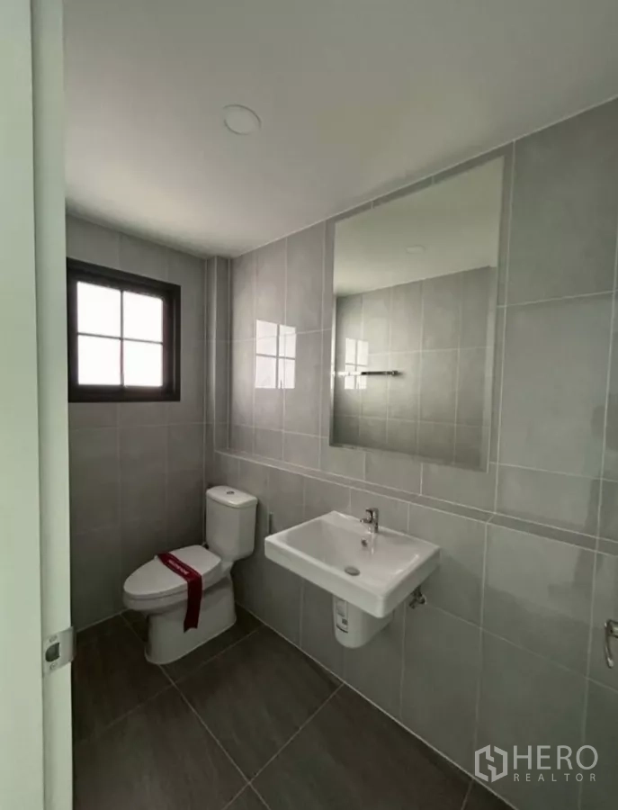Detached House for rent in Bang Phli, Samut Prakan - Compact bathroom finished in gray tiles with mirror, toilet and sink.
