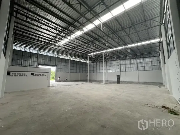 Warehouse for rent in Sai Noi, Nonthaburi - Open storage hall with tall columns, insulated metal roof and smooth concrete floor.