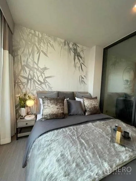 Condominium for rent in Chatuchak, Bangkok - Primary bedroom with bamboo-pattern feature wall, layered bedding and bedside lamp.