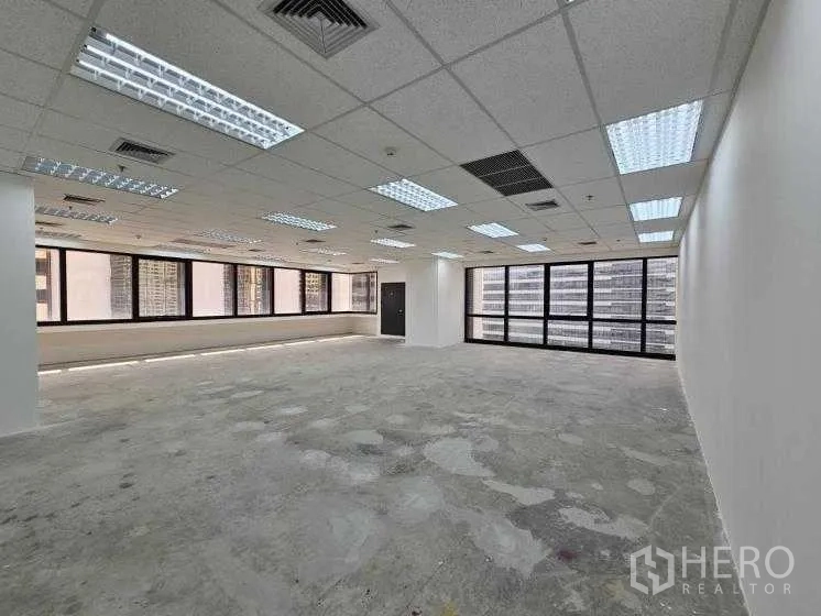 Office Space for rent in Bang Rak, Bangkok - Open workspace with grid ceiling, air vents, and full-height windows on two sides.
