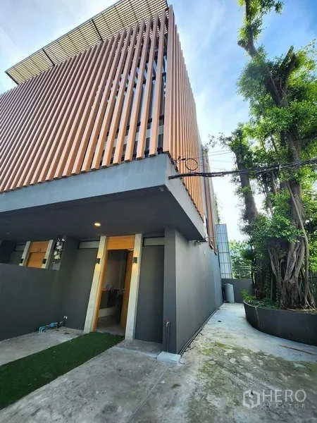 ทาวน์เฮาส์ ให้เช่าในWatthana, Bangkok - ด้านหน้าทาวน์เฮาส์สไตล์โมเดิร์น ฟาซาดระแนงไม้ ผนังโทนเทา และทางรถส่วนตัว