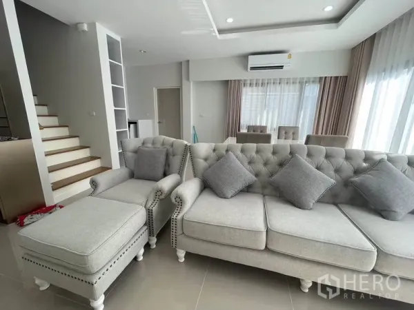 独立式住宅 出租在Prawet, Bangkok - 采光充足的客厅，灰色沙发与楼梯
