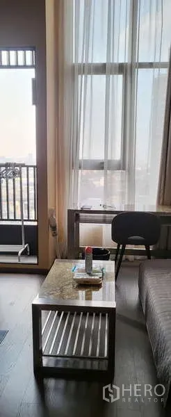 Condominium for rent - Living room corner with coffee table, small work desk, and balcony door.