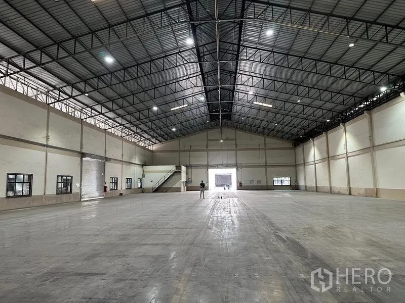 Warehouse for rent in Bang Sao Thong, Samut Prakan - Expansive warehouse interior with high steel‑truss roof, polished concrete floor and bright lighting.