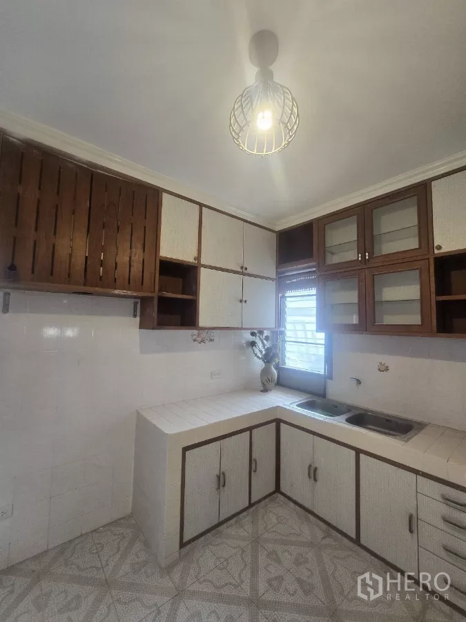 Detached House for rent in Phra Khanong, Bangkok - L-shaped kitchen with tiled counters, upper cabinets and a window for ventilation.