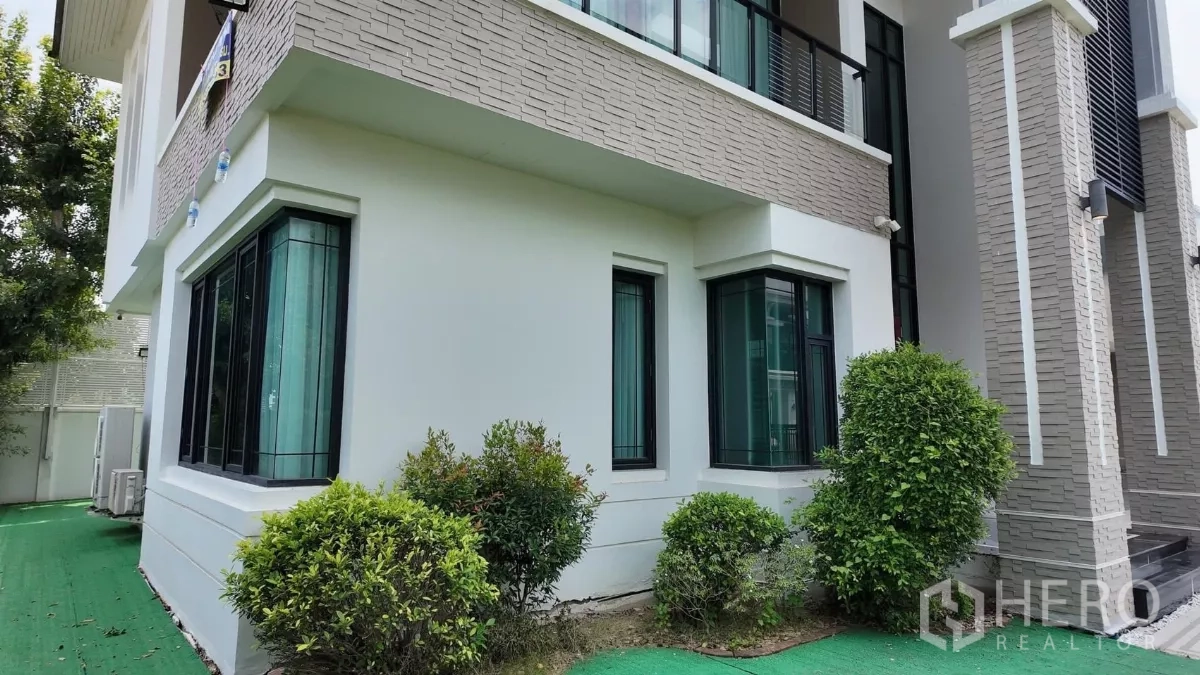 独立式住宅 出租在Bang Bon, Bangkok - 房屋侧院绿化与白色现代外立面。