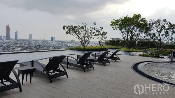 Condominium for rent in Bang Kho Laem, Bangkok - Sky terrace with sun loungers beside a reflective pool and panoramic city views at a riverside condominium in Bangkok.