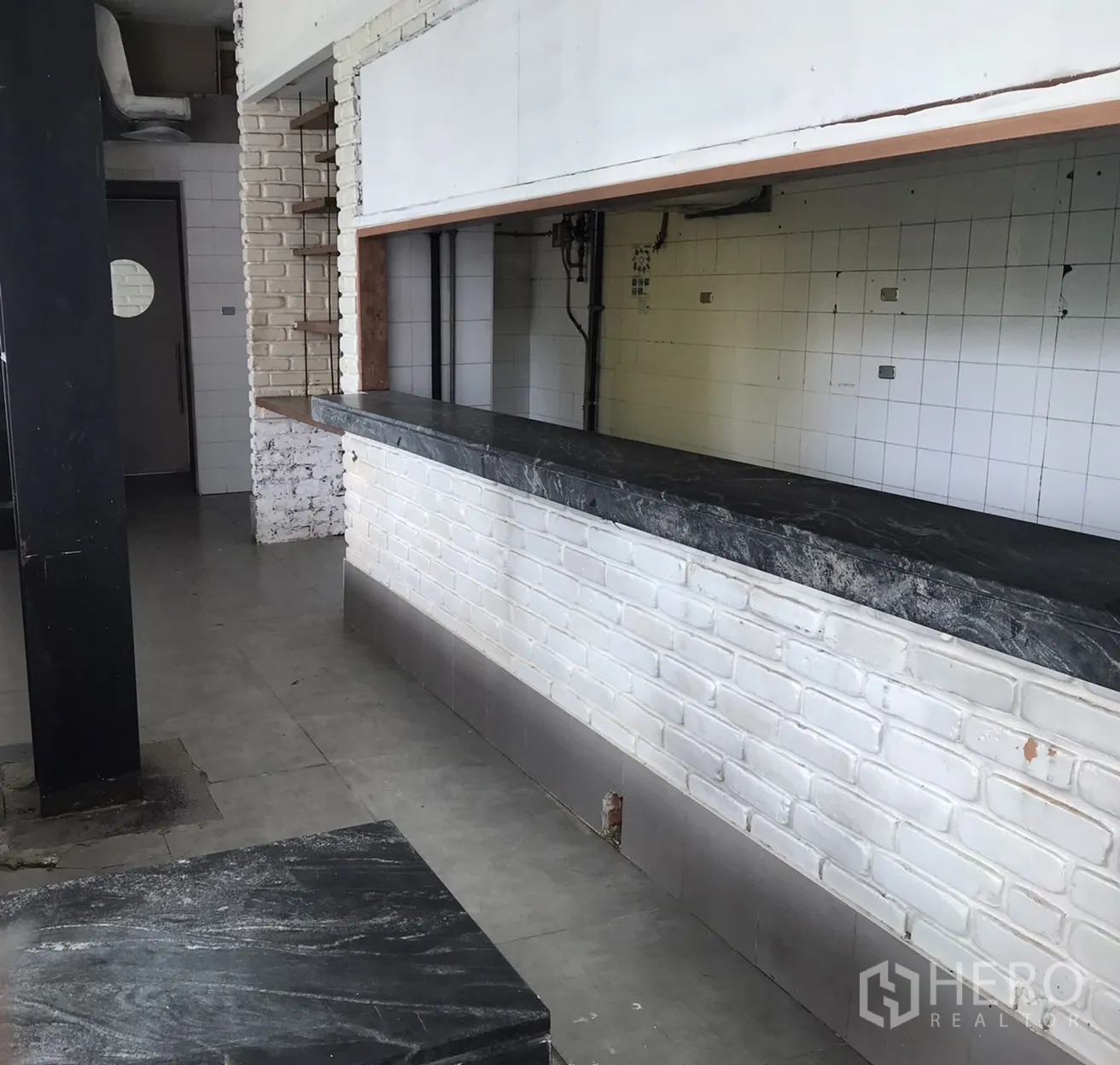 Retail Space for rent in Khlong Toei, Bangkok - Long service counter with dark stone top and white brick base inside the retail space.