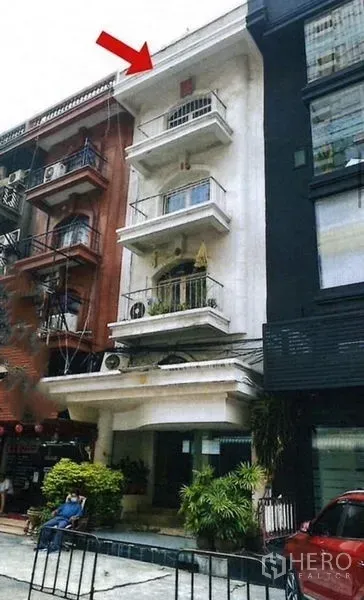 Shophouse for rent or sale in Bangkok - Four-storey shophouse facade with balconies and an arrow marker in a commercial row.