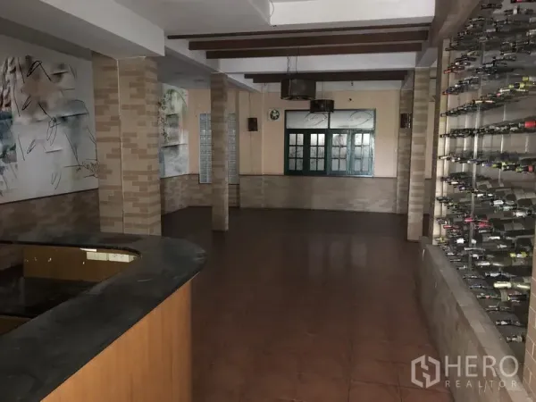 Retail Space for rent in Khlong Toei, Bangkok - Spacious indoor retail room with bar counter, tiled floor, wall-mounted display racks and exposed ceiling beams.