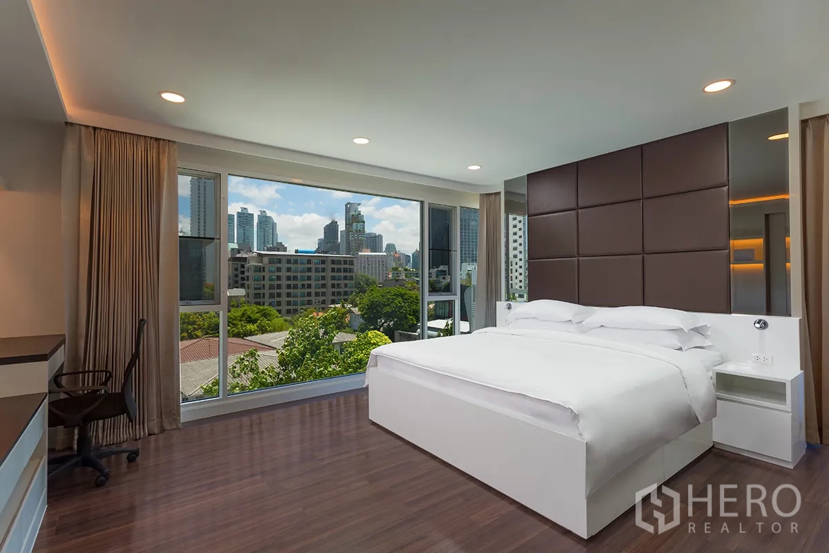 Condominium for rent in Khlong Toei, Bangkok - Spacious bedroom with large bed, floor-to-ceiling windows, and city and greenery views.