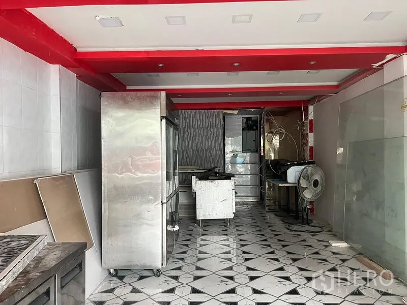 Shophouse for rent in Khlong Toei, Bangkok - Ground-floor shophouse interior with patterned tile flooring, red ceiling beams, and stainless kitchen equipment suited for F&B use.
