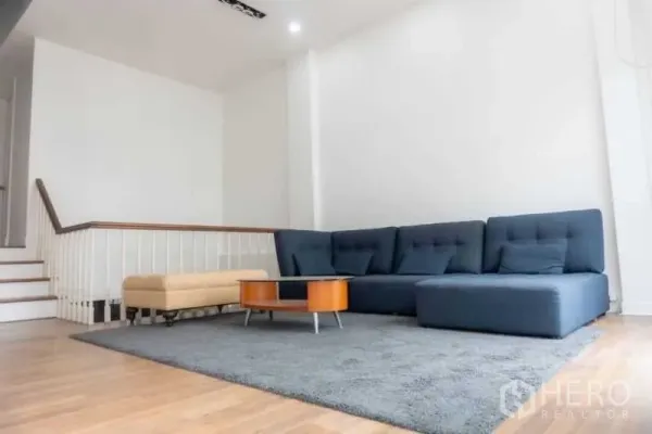 联排别墅 出租在Bang Kapi, Bangkok - 分层客厅，大型L型沙发、灰色地毯与楼梯