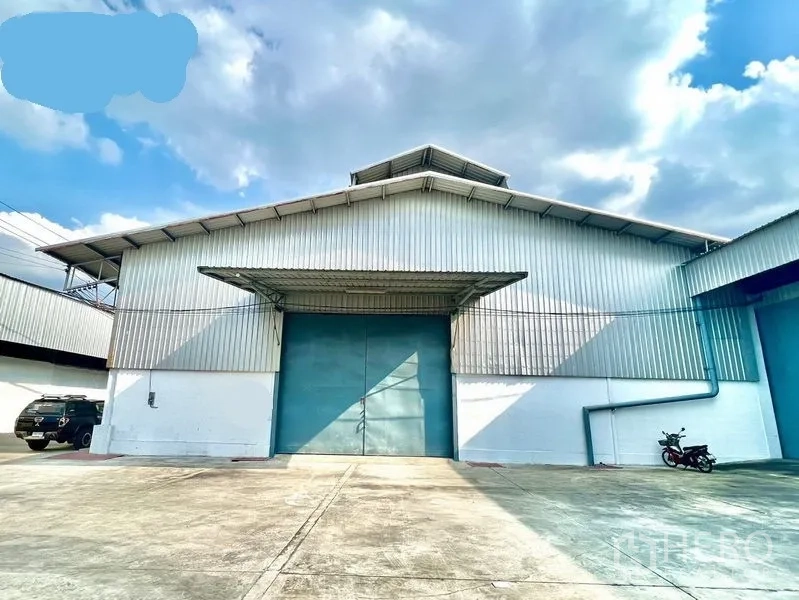 คลังสินค้า ให้เช่าในPak Kret, Nonthaburi - ด้านหน้าโกดังโครงเมทัลที่ปากเกร็ด พร้อมลานคอนกรีตกว้างและประตูบานเลื่อนสีฟ้าใต้กันสาด