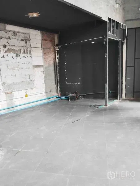 Retail Space for rent in Watthana, Bangkok - Unfinished interior with gray tiled floor, exposed brickwork and visible water pipes.