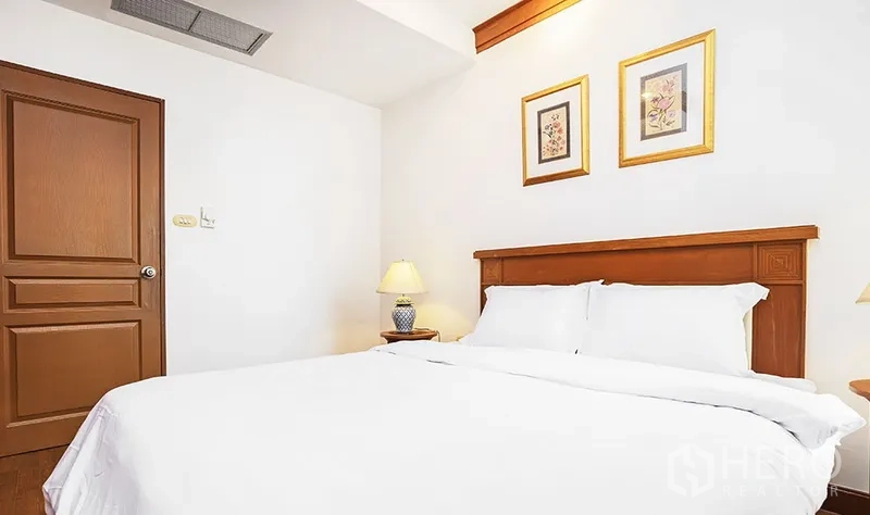 公寓 出租在Pathum Wan, Bangkok - 主卧室，白色床品、木质床头和床头灯。