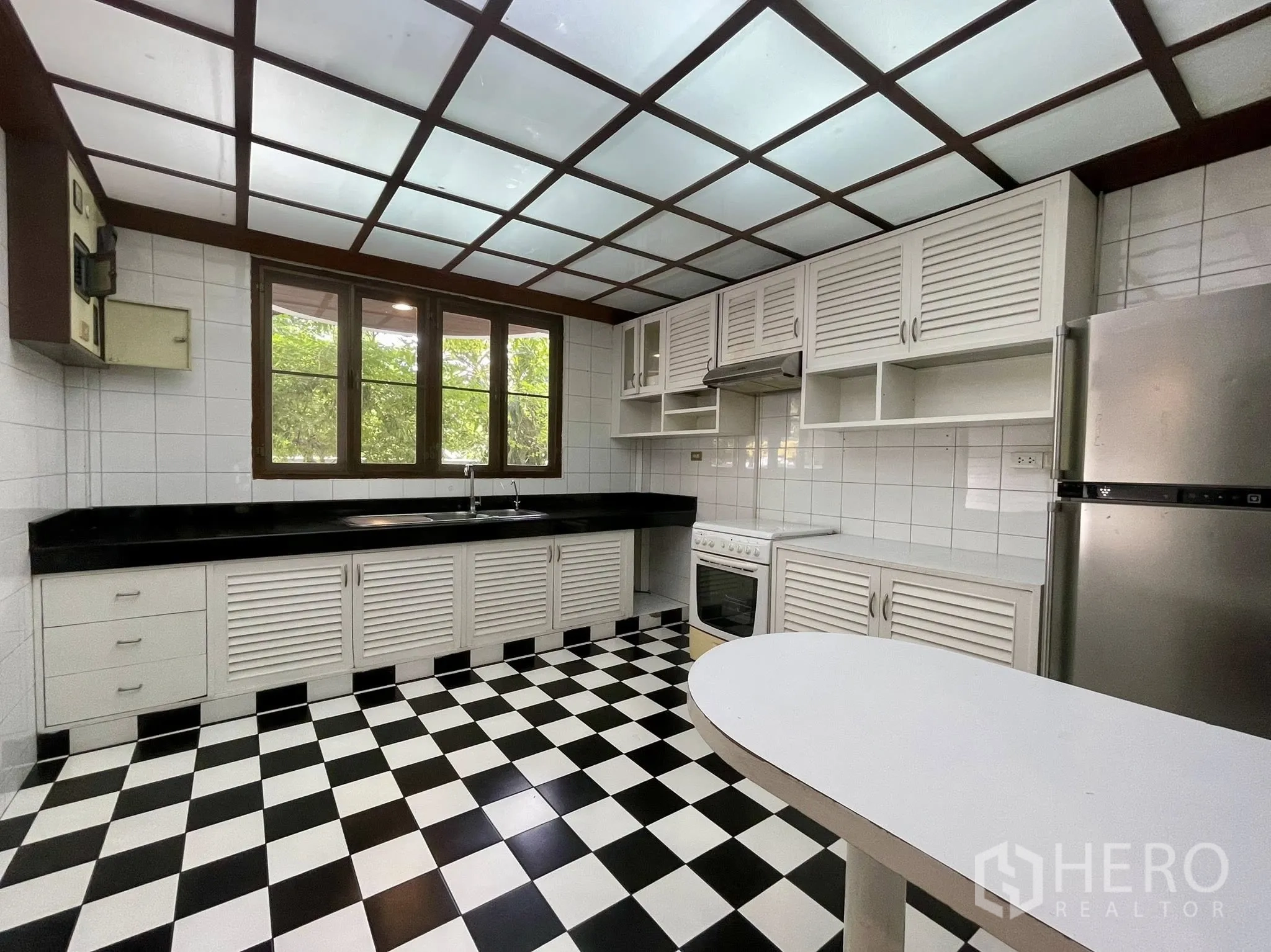 Detached House for rent in Pathum Wan, Bangkok - Family kitchen with black-and-white checkered floor, white cabinets, and appliances.