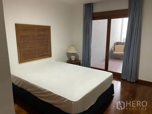 公寓 出租在Pathum Wan, Bangkok - 卧室带推拉玻璃门与蓝色窗帘，连接私密阳台。