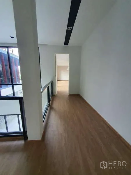 Detached House for rent in Phra Khanong, Bangkok - Upstairs corridor with wood flooring and glass balustrade facing the internal courtyard.