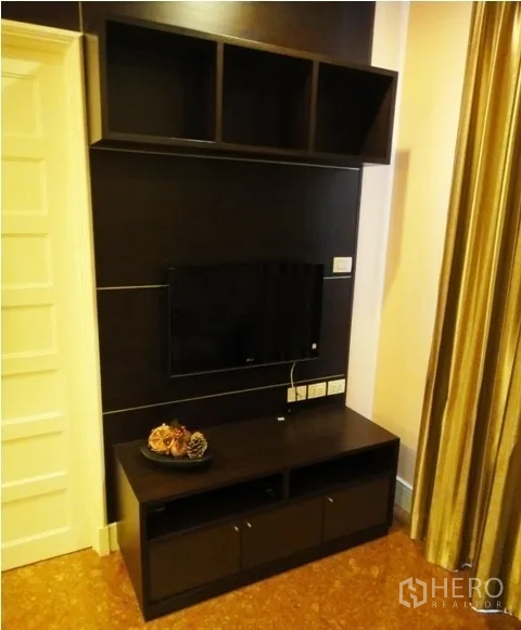 Condominium for rent in Khlong Toei, Bangkok - Built-in dark wood TV wall with shelving and media console in a cozy living area.
