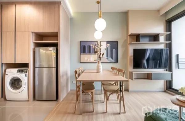Condominium for rent in Chatuchak, Bangkok - Dining corner with globe pendant lights, framed art and TV wall next to the balcony door.