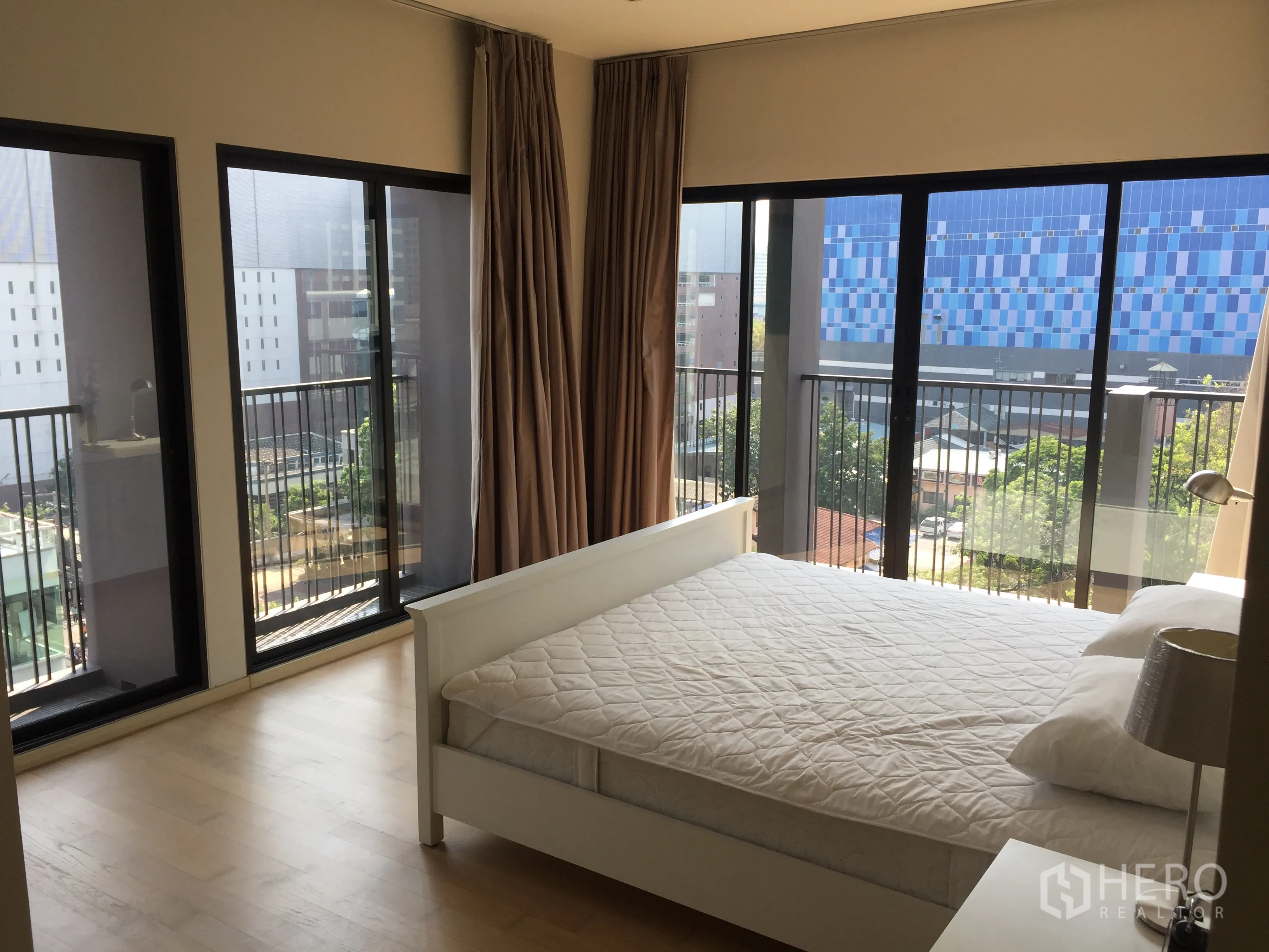 Condominium for rent or sale in Watthana, Bangkok - Corner bedroom with floor-to-ceiling windows, twin balconies and skyline views.