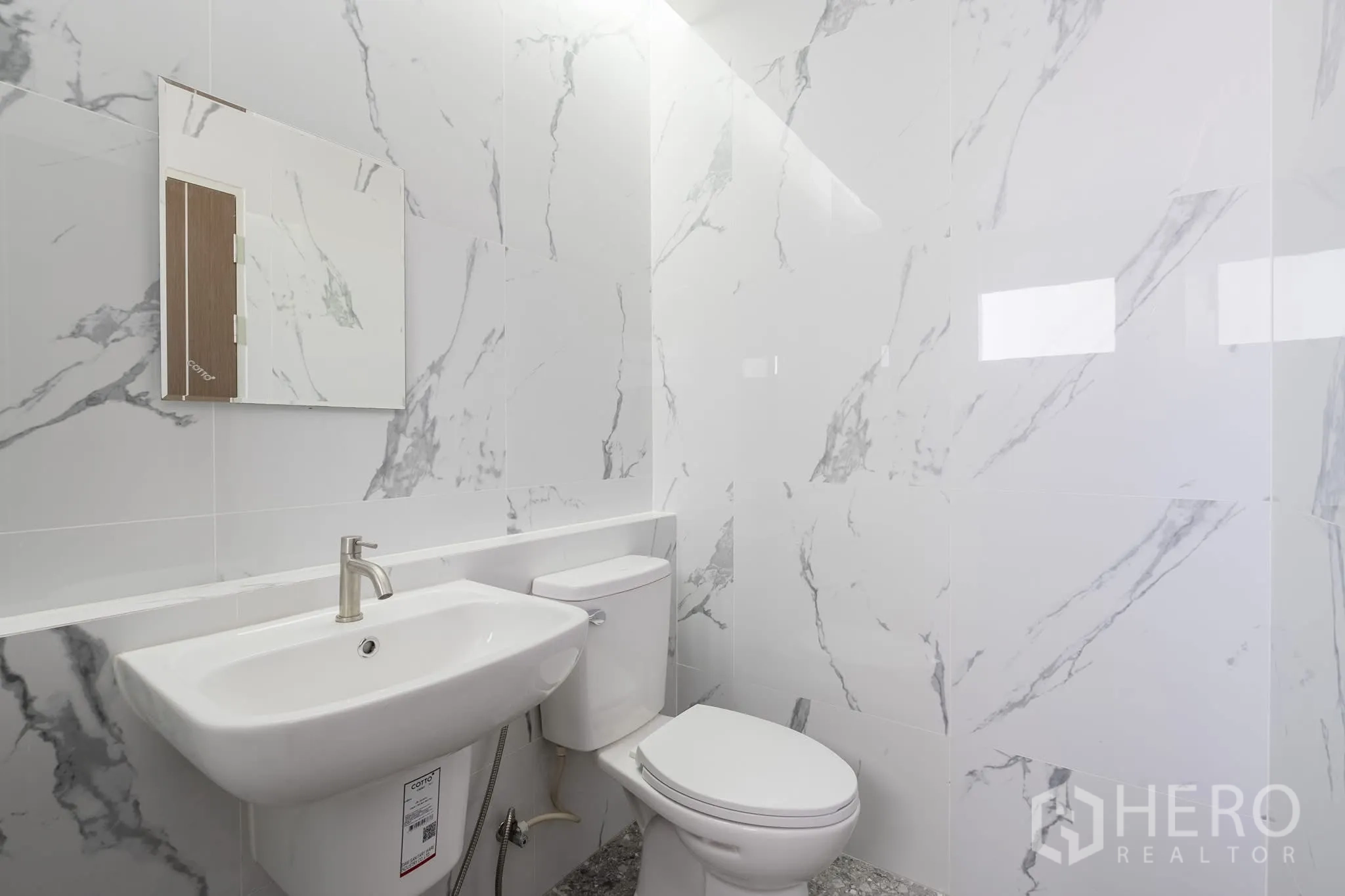 Home Office for rent in Khlong Toei, Bangkok - Compact bathroom with marble-style tiles, wall mirror, basin and toilet.
