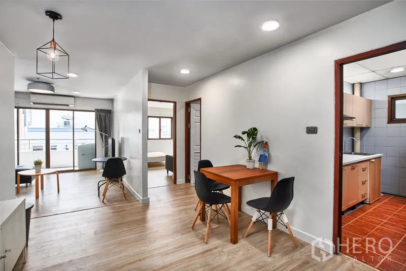 Condominium for rent in Watthana, Bangkok - Dining nook and hallway leading to bedrooms with wood flooring and balcony access.