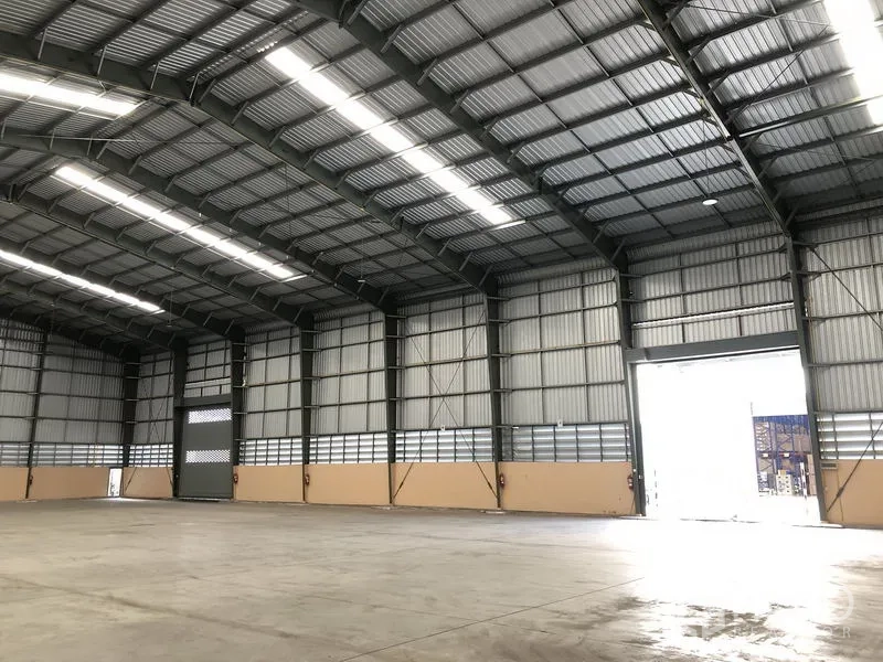 货栈 出租在Pathum Thani - 仓库内景，卷闸门入口、通风墙体与宽阔装卸空间
