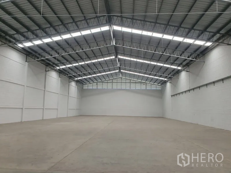 货栈 出租在Khlong Luang, Pathum Thani - 仓库内部空间开阔，钢桁架高屋顶与采光带，混凝土地面。