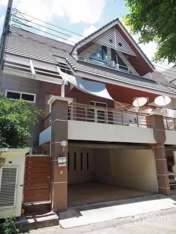 联排别墅 出租在Wang Thonglang, Bangkok - 三层联排别墅外观，山墙屋顶，阳台与带顶双车位车库。