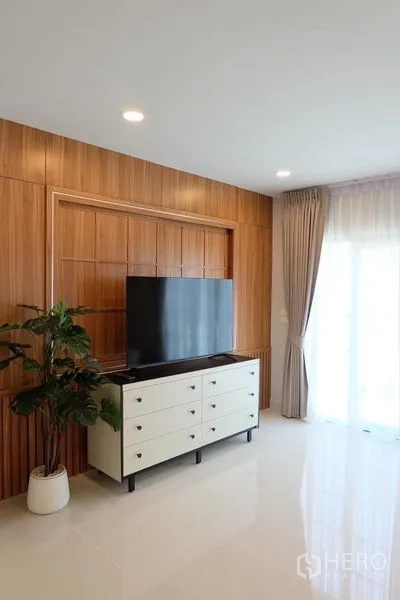Detached House for rent in Bang Phli, Samut Prakan - Media wall with wood paneling, white drawer console and flat-screen TV.