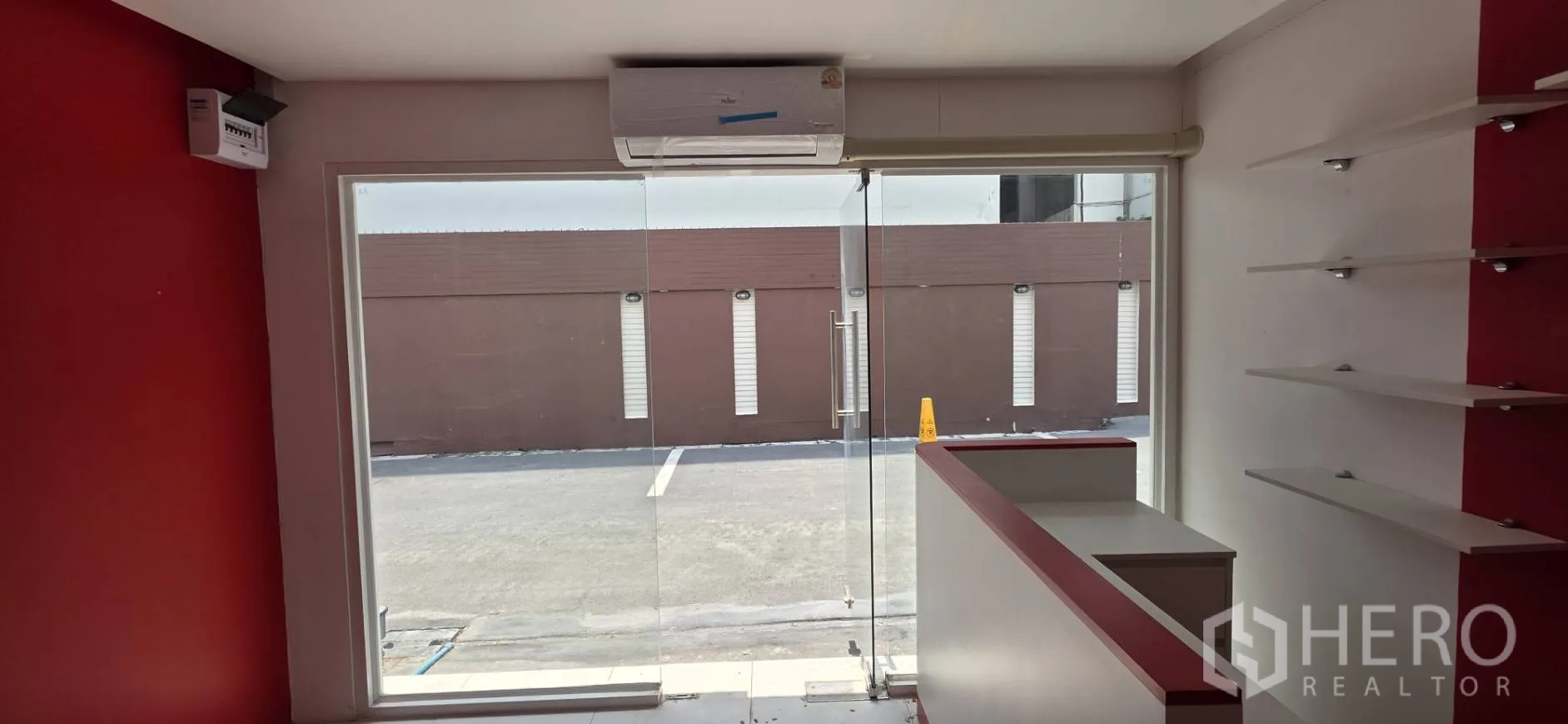 零售空间 for rent in Watthana, Bangkok - 从店内望向玻璃入口，门上方设分体空调。