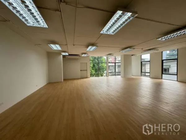 Office Space for rent in Sathon, Bangkok - Spacious office interior with large window wall overlooking greenery, exposed ceiling services and even lighting.