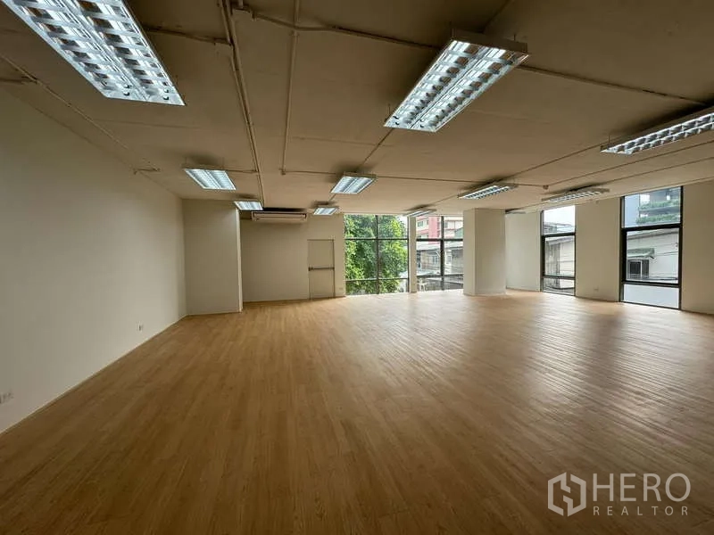 Office Space for rent in Sathon, Bangkok - Spacious office interior with large window wall overlooking greenery, exposed ceiling services and even lighting.