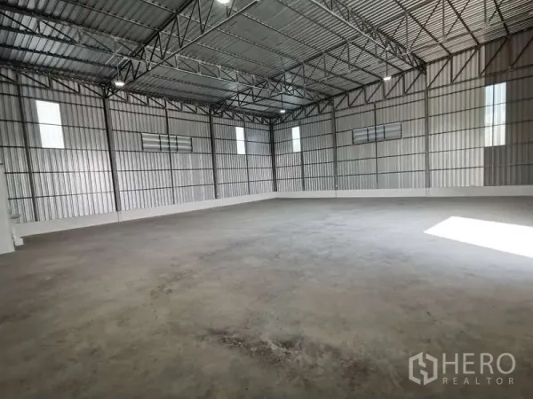 Warehouse for rent in Prawet, Bangkok - Spacious warehouse interior with high steel truss ceiling, concrete floor and vented windows.