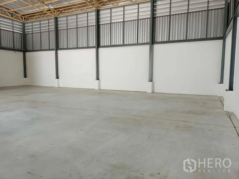Warehouse for rent in Suan Luang, Bangkok - Open storage hall with steel columns, ventilated panels, and smooth concrete flooring.
