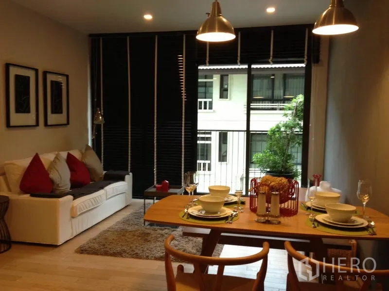 คอนโด ให้เช่าในWatthana, Bangkok - ห้องนั่งเล่นเชื่อมทานอาหาร โซฟาพร้อมพรม โต๊ะจัดอาหารสี่ที่ และประตูกระจกบานเลื่อนออกสู่ระเบียง