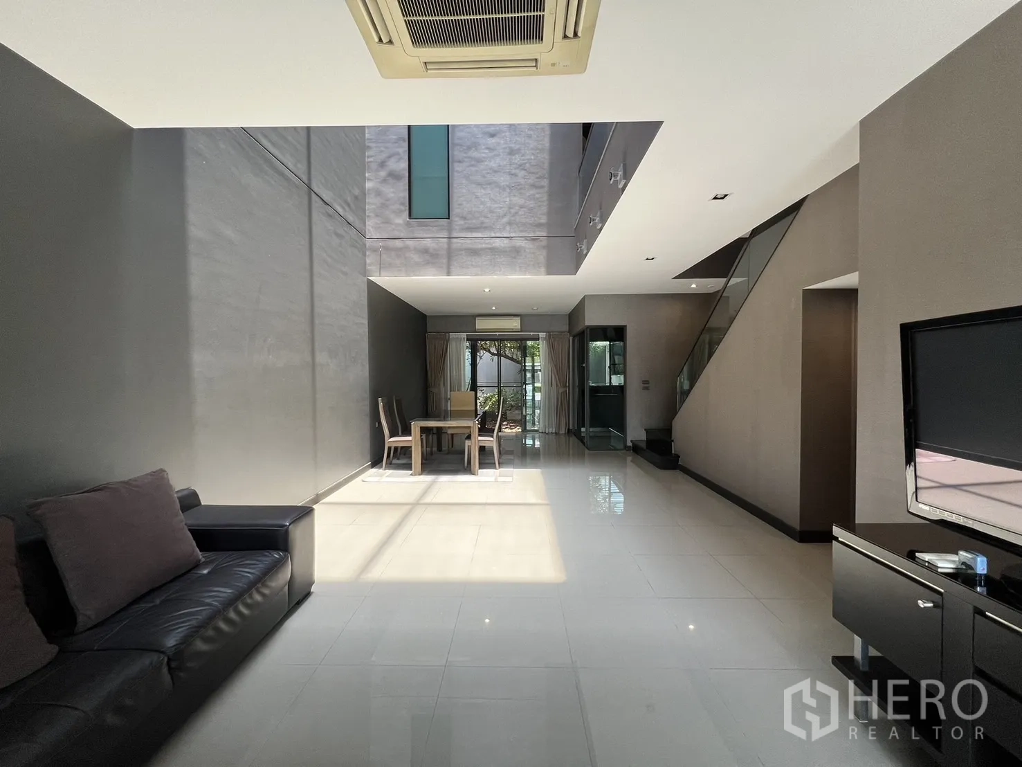 Townhouse for rent in Lat Phrao, Bangkok - Sunlit lounge showing tall atrium void and dining zone at the rear.